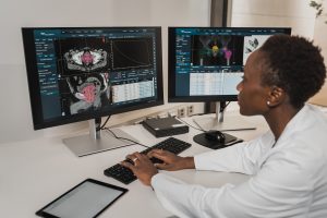 A medical professional working diligently, typing on the keyboard of a computer with focus and expertise