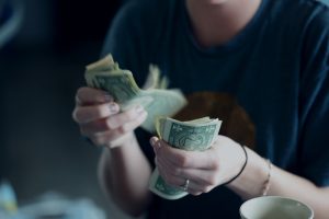 a person counting dollar bills, signifying consideration of medical costs