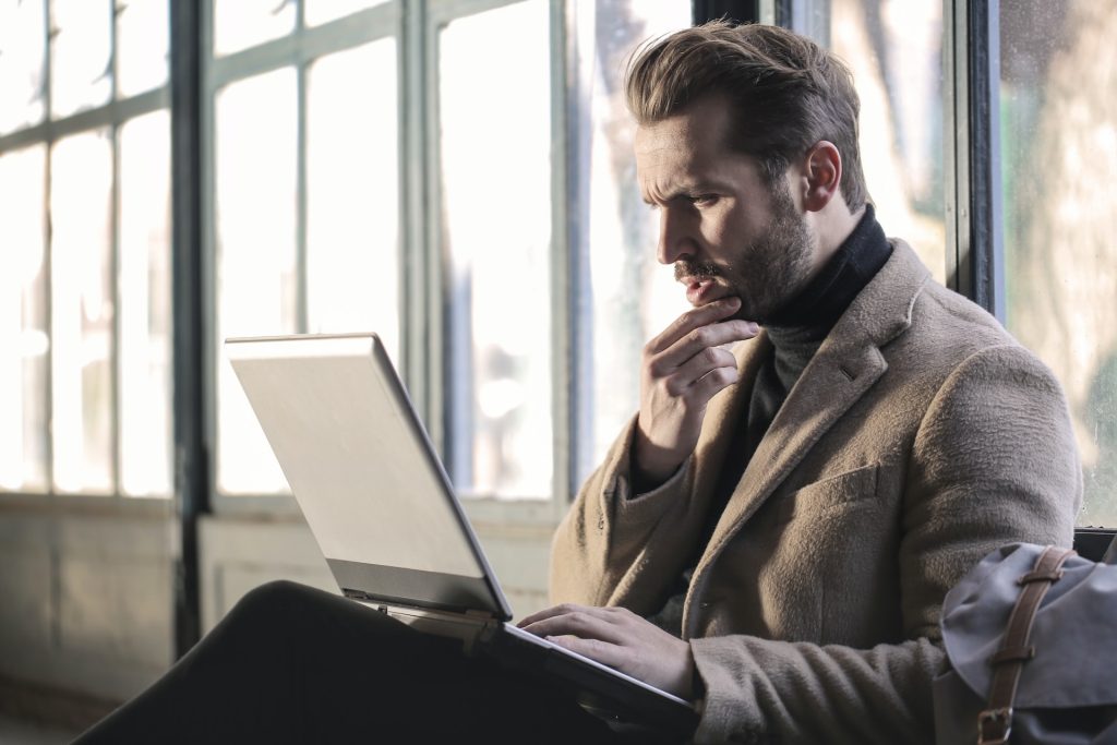 A man looks at a computer, taking in information, considering information about healthshares