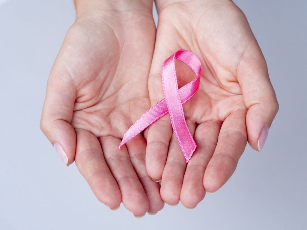 a pair of hands holding a pink ribbon, signifying breast cancer, for which mammograms are now shareable at Zion HealthShare