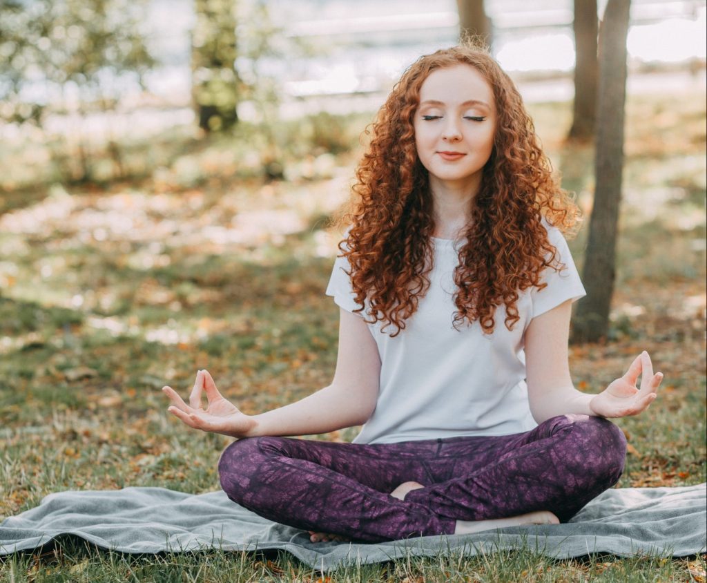 a woman meditating in nature, focusing on mental wellness